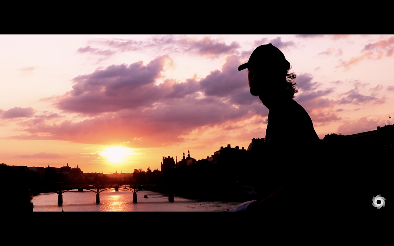 Photo de Louis assis sur un pont à Paris devant le coucher de soleil, extrait du projet “Je Vagabonde”.